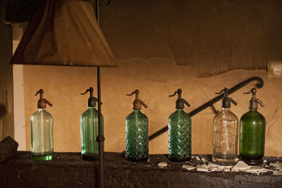 Glass bottles on wooden log against wall