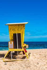 Lifeguard hut on beach against blue sky