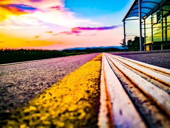 Surface level of railroad track against sky during sunset