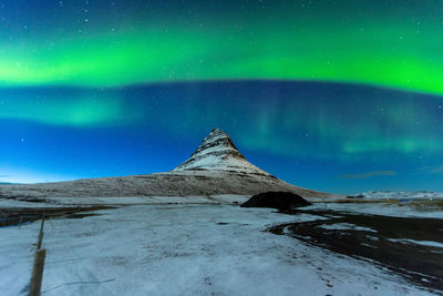 Scenic view of snowcapped mountain against sky at night