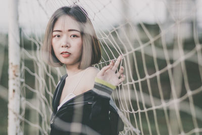 Portrait of beautiful young woman standing at goal