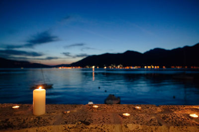 Close-up of burning candle against blue sky at twilight