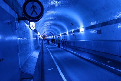People walking in illuminated tunnel