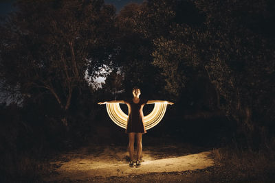 Full length of woman standing by tree in forest