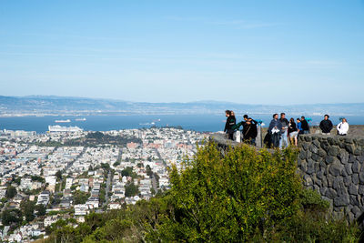 People looking at sea by cityscape against sky
