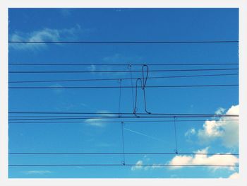 Low angle view of power lines against blue sky