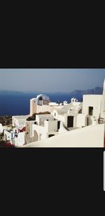 Buildings by sea against clear sky