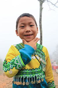 Portrait of smiling boy in traditional clothing standing against sky