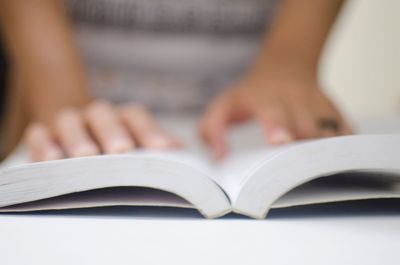 Midsection of woman reading book on table