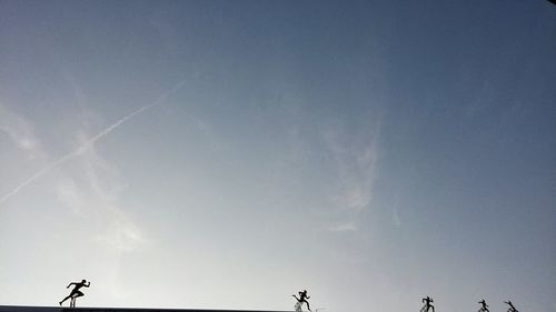 Low angle view of vapor trails against blue sky