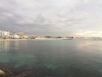 Scenic view of sea by buildings against sky