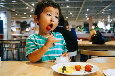 Cute boy eating tomato in restaurant
