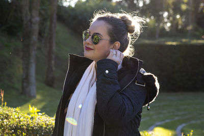 Woman wearing sunglasses and warm clothing while standing outdoors