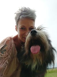 Portrait of woman with dog against sky