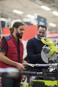 Salesman explaining machinery to male customer in hardware store