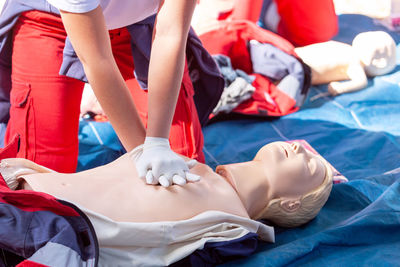 Midsection of person practicing cpr on dummy outdoors