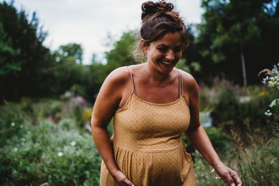 Smiling pregnant woman outside in nature wearing a yellow dress