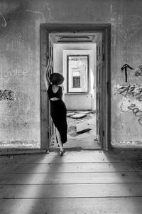 Rear view of woman standing against door of building