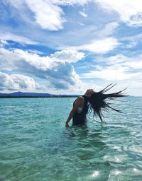 Young woman in bikini on sea against sky