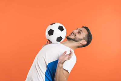 Midsection of man playing soccer ball against yellow background