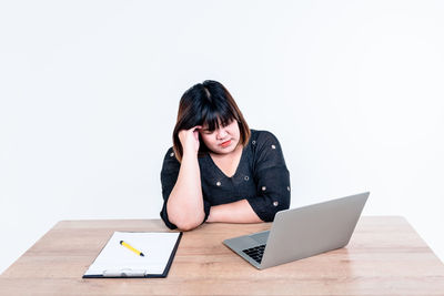 Young woman using mobile phone while sitting on table