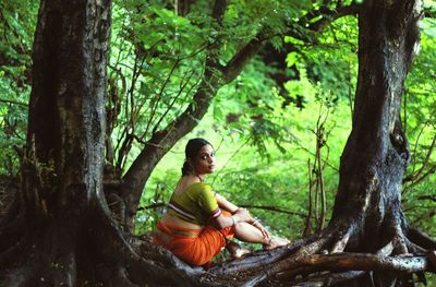 Woman sitting on tree trunk in forest