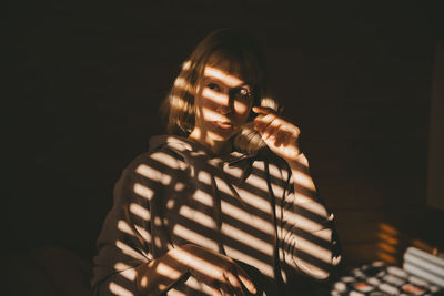 Portrait of woman standing against black background