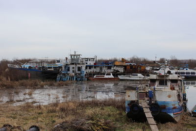 Boats moored by river against sky