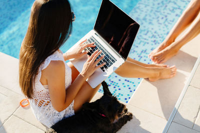 High angle view of woman using laptop by swimming pool