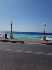 Street light on beach against clear blue sky