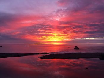 Scenic view of sea against dramatic sky during sunset