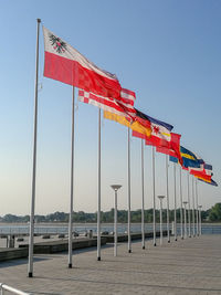 Low angle view of flags against clear blue sky