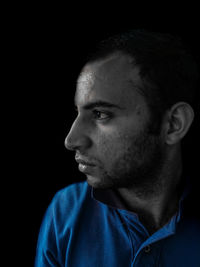 Close-up portrait of young man against black background