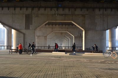 People walking under bridge in city