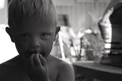 Close-up portrait of shirtless boy with pacifier in mouth