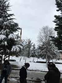 People on snow covered land against sky