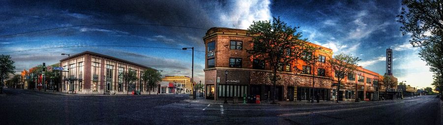 Road leading towards buildings against cloudy sky