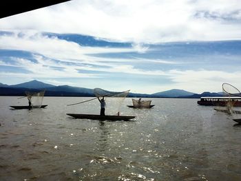 Boats in sea with mountain range in background