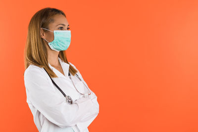 Female doctor holding stethoscope against yellow background