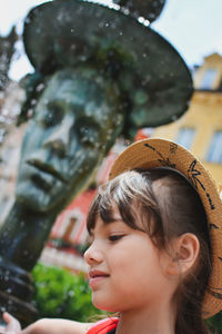 Low angle view of thoughtful girl looking away while standing against building