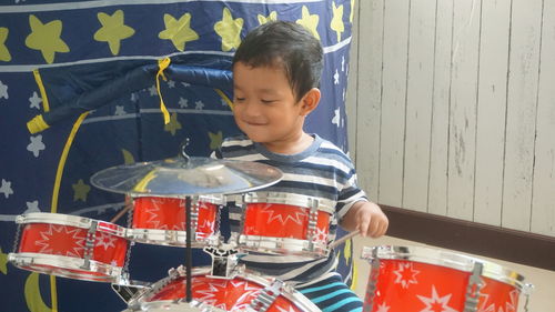 Cute boy playing drums at home