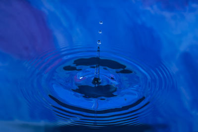 Close-up of drop falling on blue water