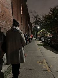 Rear view of man walking on street at night