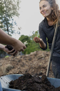 Hands checking dirt on wheelbarrow