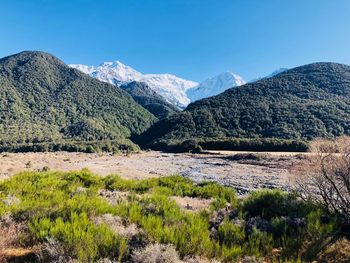 Scenic view of landscape and mountains against blue sky