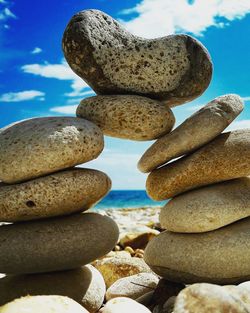 Close-up of stacked stones at beach against sky