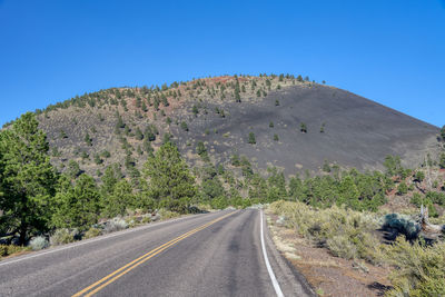 Road by mountain against clear blue sky