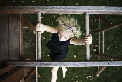 Overhead view of carefree girl hanging on monkey bars at playground