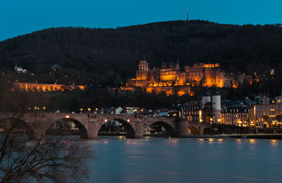 Illuminated bridge over river at night