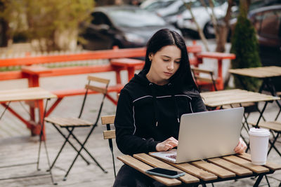 Young woman using laptop at cafe